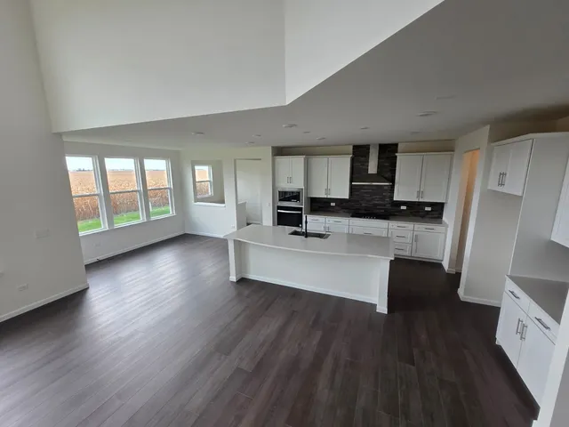 a large open kitchen with stainless steel appliances a refrigerator a stove a sink dishwasher with wooden floor and cabinets