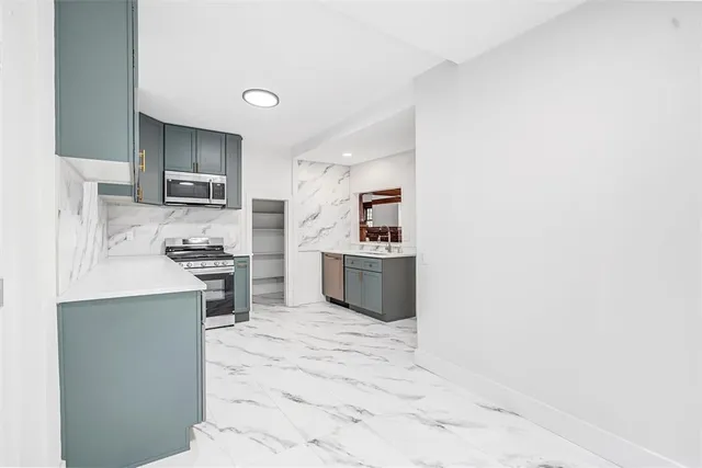 a kitchen with stainless steel appliances a stove top oven a sink a counter top space and cabinets