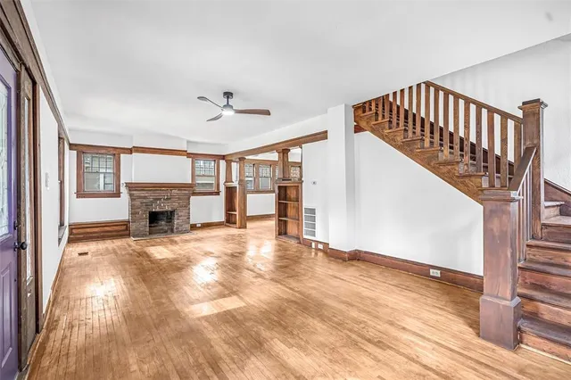 a view of an empty room with wooden floor fireplace and a window