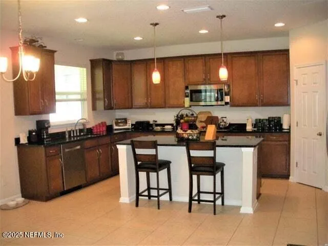 a kitchen with granite countertop a stove a sink a dining table and chairs