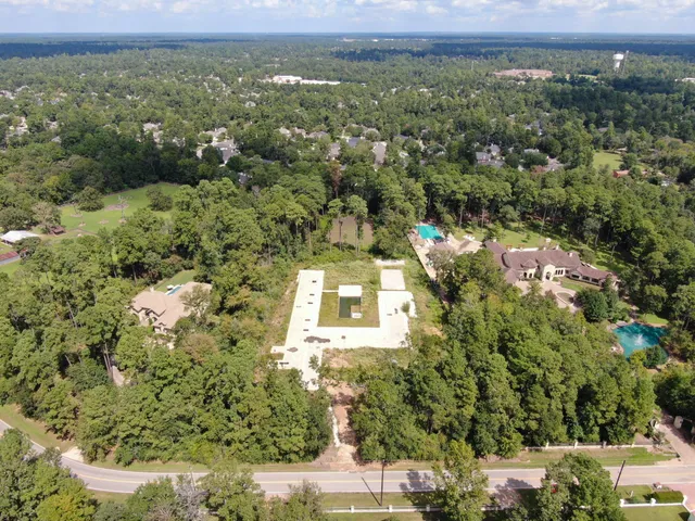 an aerial view of a residential houses with outdoor space and trees