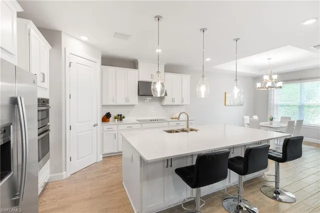 a kitchen with stainless steel appliances granite countertop a sink a stove a refrigerator and island with wooden floor