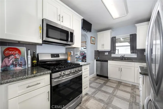 a kitchen with stainless steel appliances granite countertop a stove a sink and a microwave