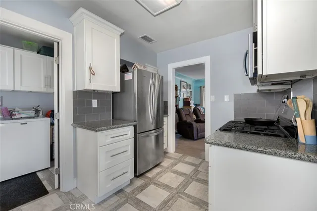 a kitchen with granite countertop a refrigerator stove and sink