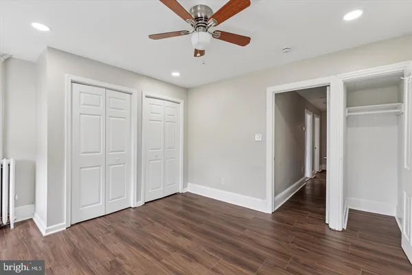 an empty room with wooden floor cabinet and a ceiling fan