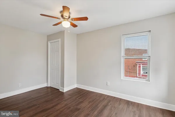 a view of an empty room with wooden floor and a ceiling fan