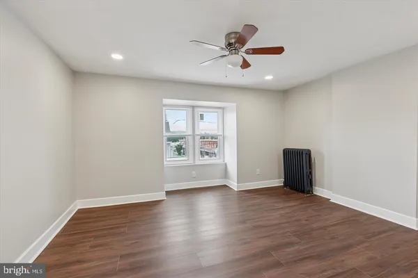 a view of an empty room with a window and wooden floor