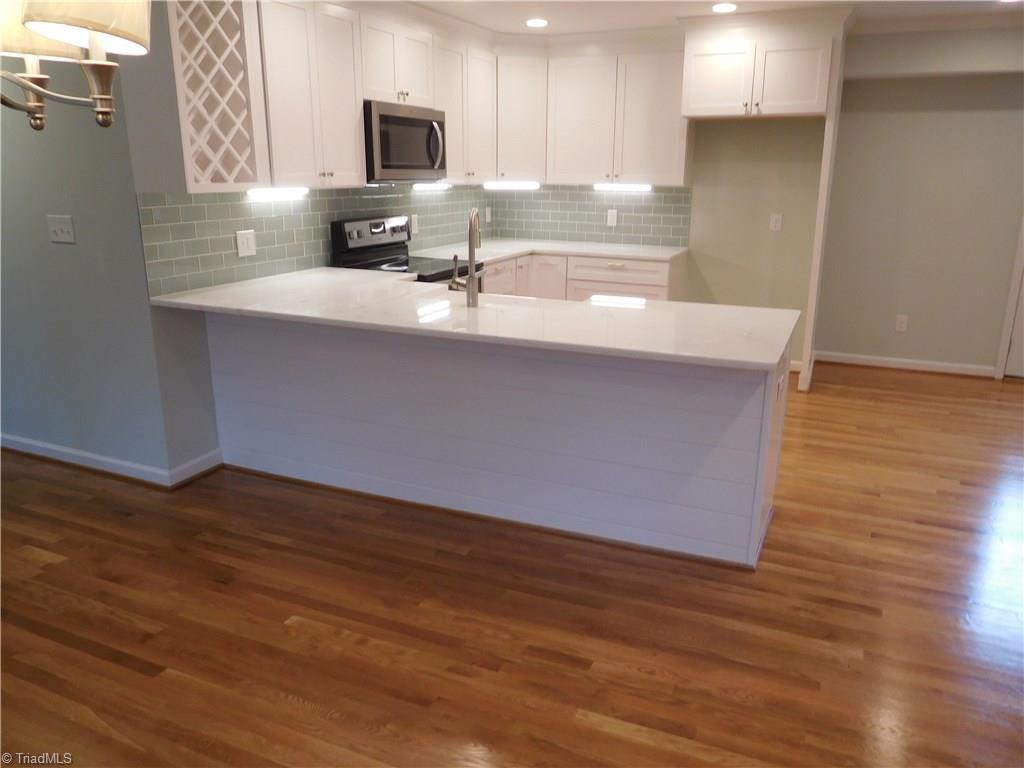 144 Hauser Road Lewisville, NC 27023 - Photo 3 of 21 All new Kitchen: white cabinets w/soft close drawers, granite counters, tile backsplash, built-in wine rack, farm sink, under cabinet lighting & Stainless Steel built-in MW, DW & range/oven.