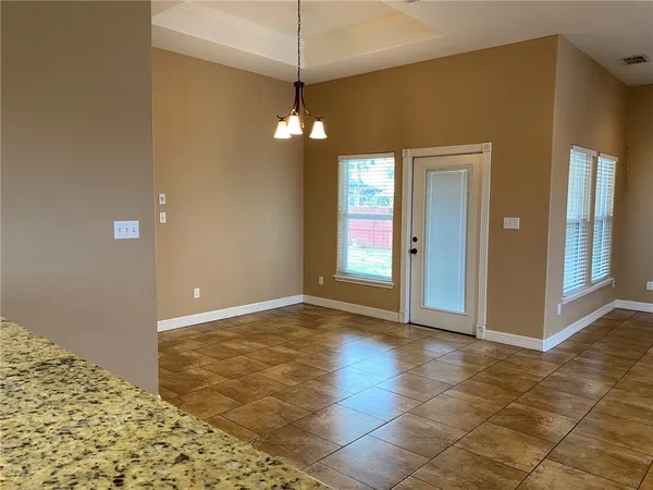 a view of a livingroom with a chandelier fan and kitchen view