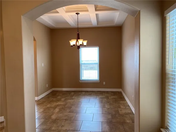 an empty room with chandelier fan and windows