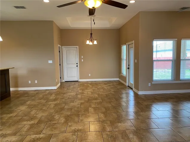 a view of an empty room with window and chandelier fan