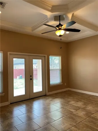 a view of an empty room with window and chandelier fan
