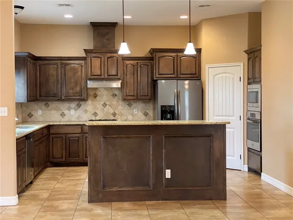 a kitchen with kitchen island granite countertop a refrigerator and cabinets