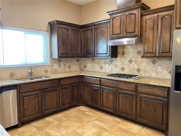 a kitchen with granite countertop a sink stainless steel appliances and cabinets