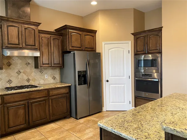 a kitchen with stainless steel appliances granite countertop a refrigerator and a sink