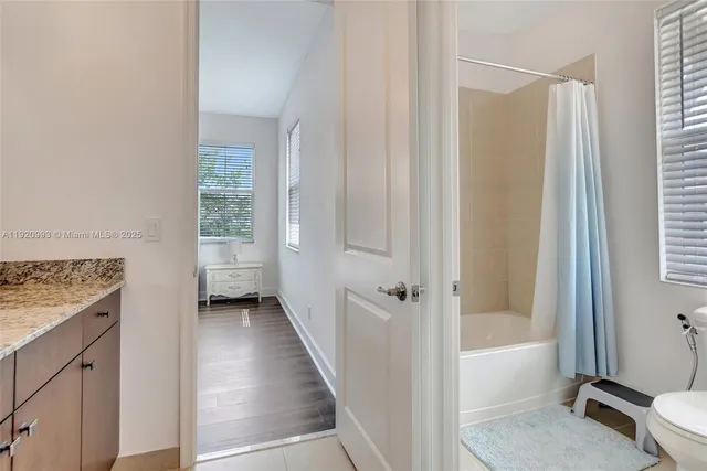 a bathroom with a granite countertop bathtub shower sink vanity and toilet