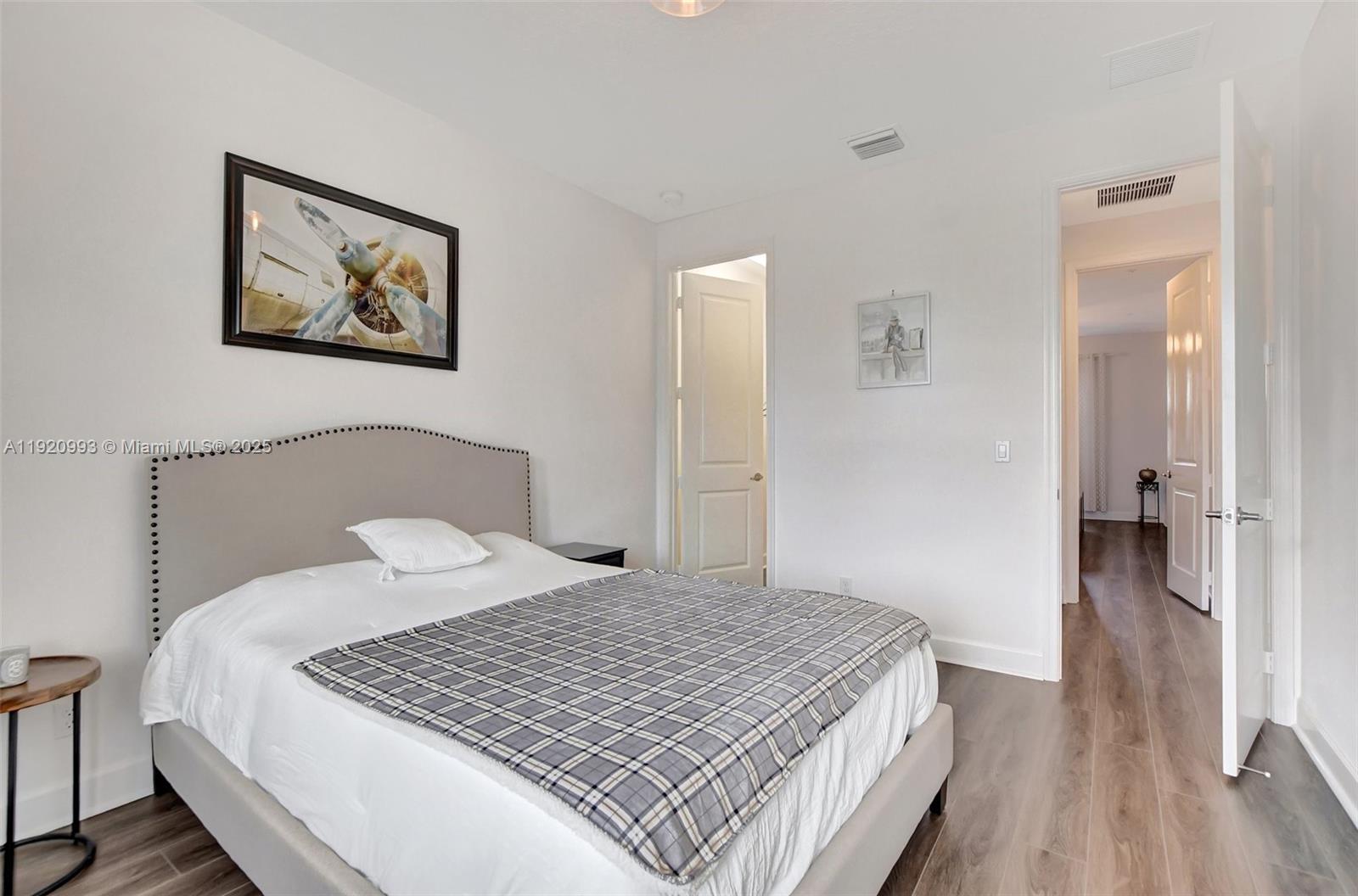 6657 Quiet Wave Trail, Unit 100 Boca Raton, FL 33433 - Photo 27 of 40 a bedroom with a bed and wooden floor