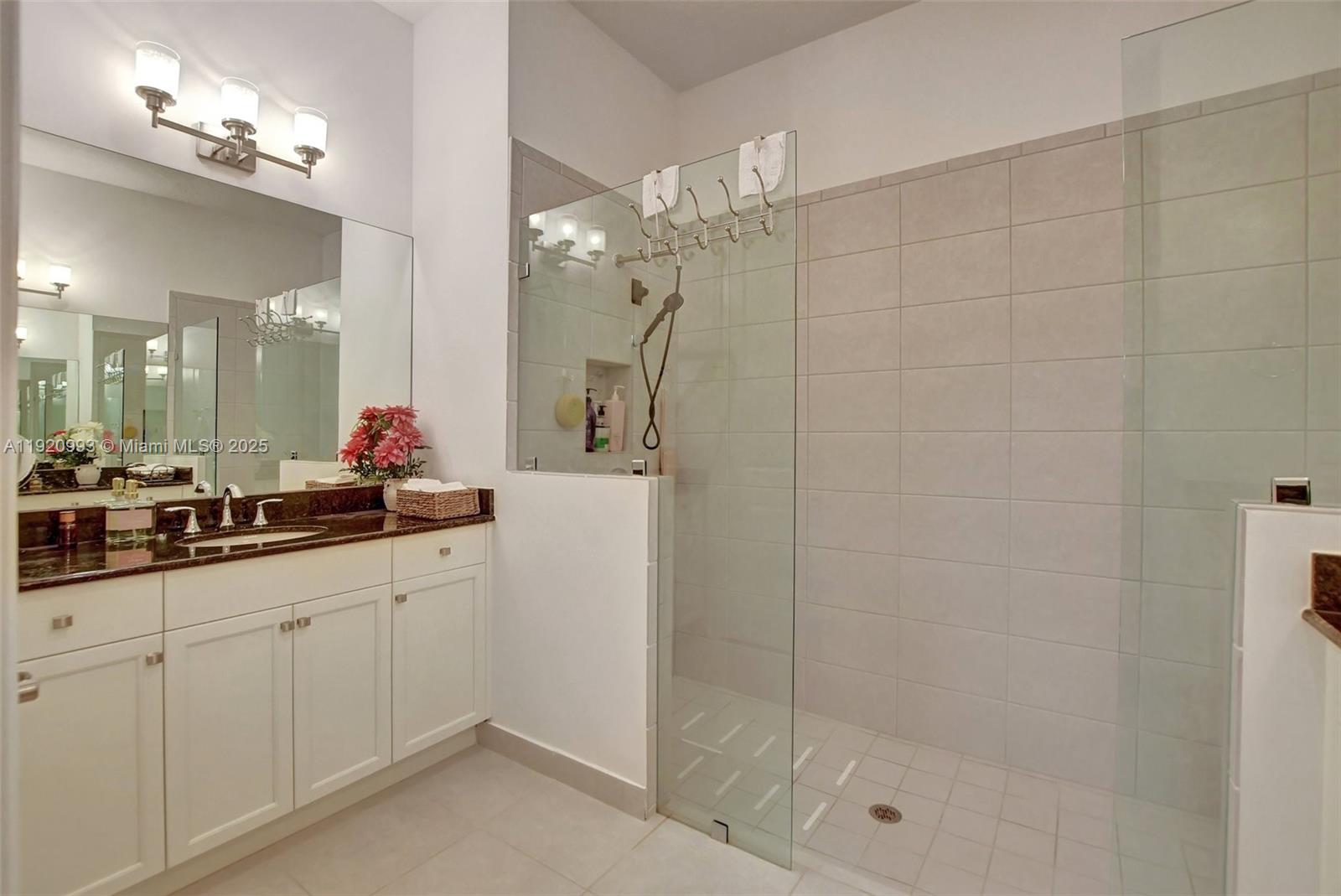 6657 Quiet Wave Trail, Unit 100 Boca Raton, FL 33433 - Photo 29 of 40 a bathroom with a shower a sink and a mirror