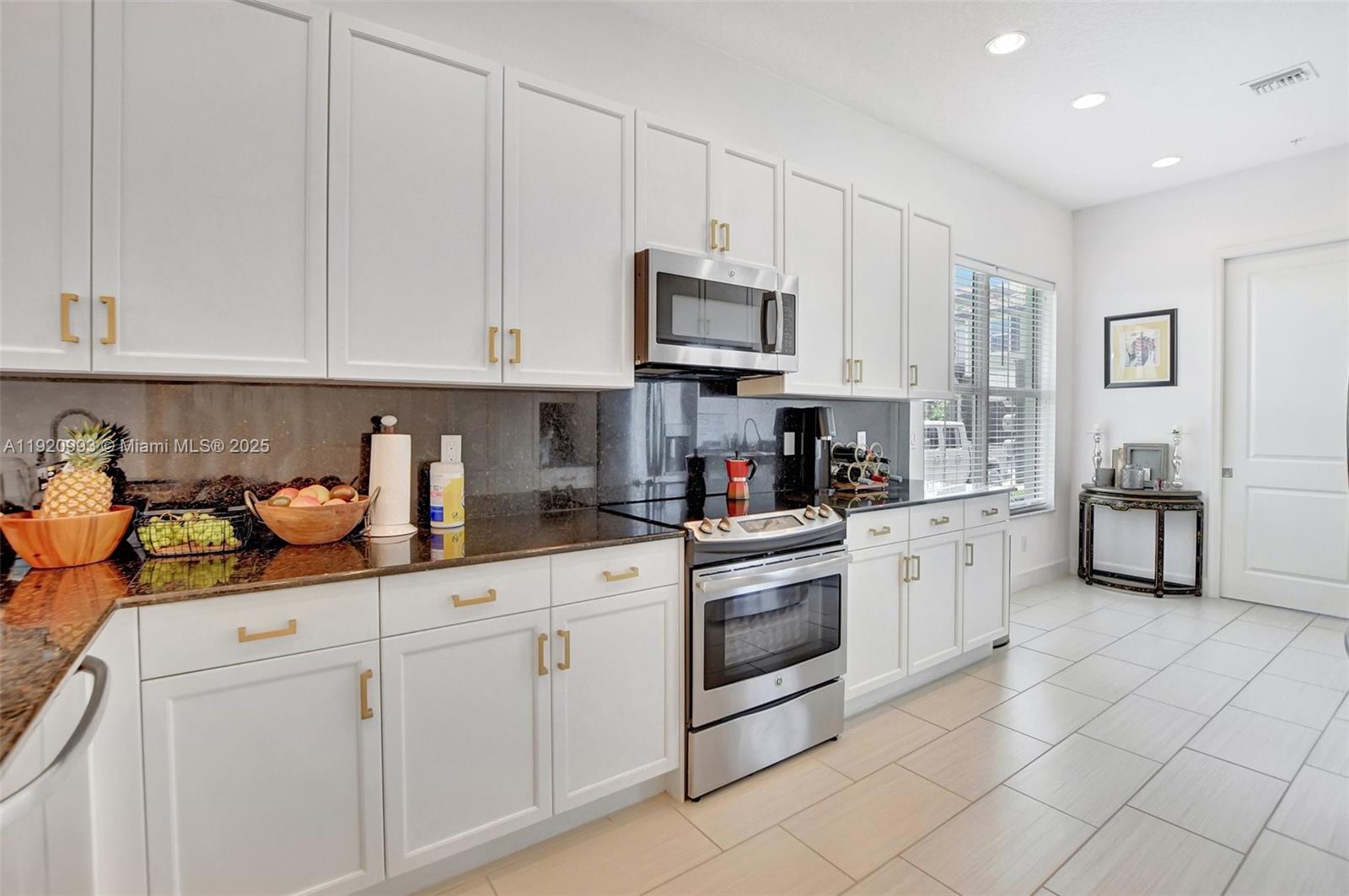 6657 Quiet Wave Trail, Unit 100 Boca Raton, FL 33433 - Photo 7 of 40 a kitchen with stainless steel appliances granite countertop a sink and a stove