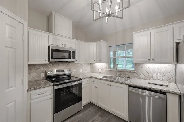 a kitchen with stainless steel appliances granite countertop a sink a stove a microwave and cabinets