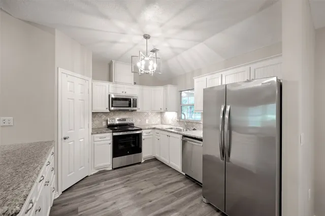 a kitchen with stainless steel appliances granite countertop a refrigerator a stove microwave and a sink with wooden floor