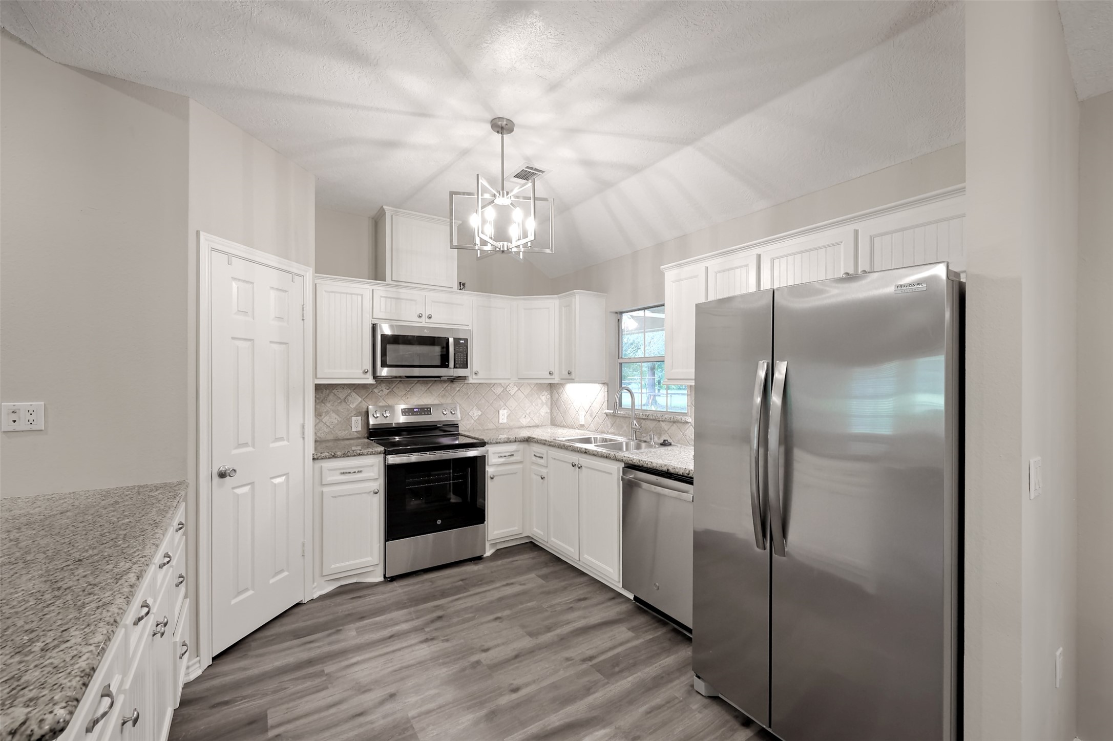 3131 Sapp Road Conroe, TX 77304 - Photo 12 of 48 a kitchen with stainless steel appliances granite countertop a refrigerator a stove microwave and a sink with wooden floor