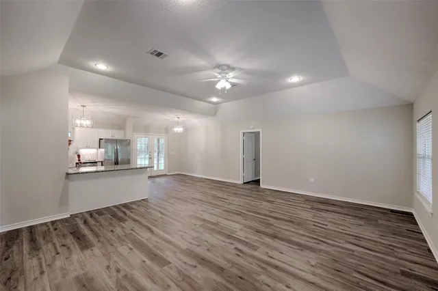 an empty room with wooden floor ceiling fan and windows