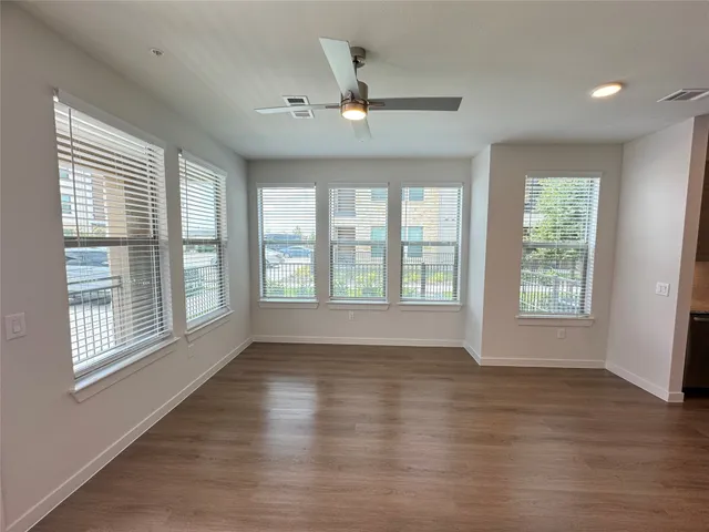 a view of an empty room with wooden floor and a window