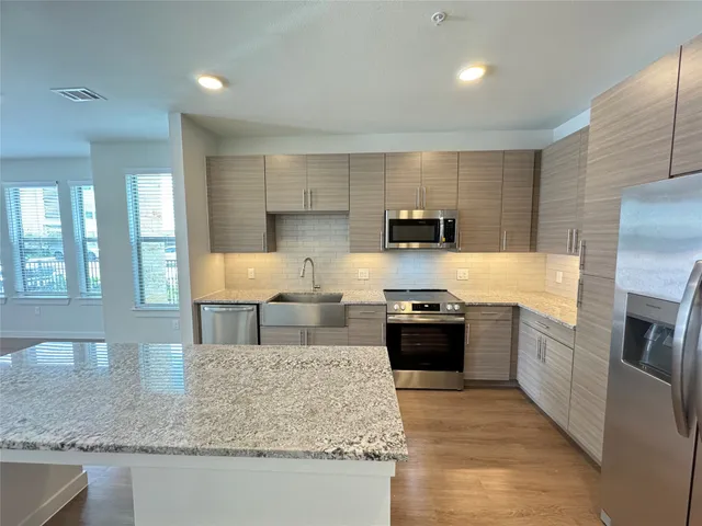 a kitchen with stainless steel appliances granite countertop a sink stove and refrigerator