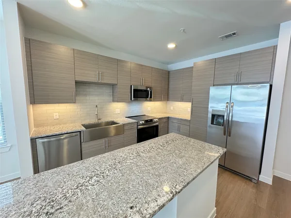 a kitchen with stainless steel appliances granite countertop a sink refrigerator and microwave