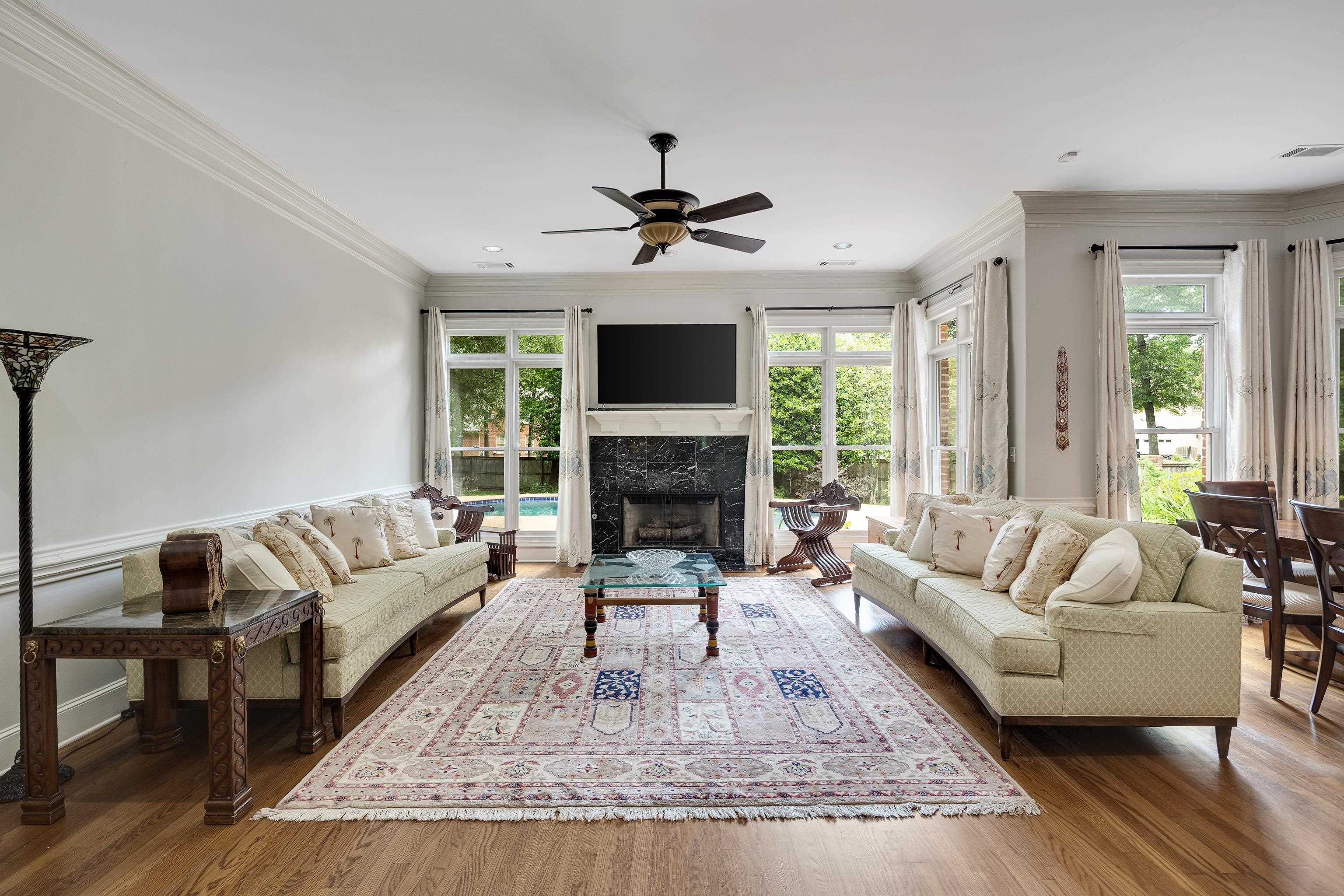 350 Bluff Ridge Cove Memphis, TN 38018 - Photo 23 of 37 Bright living room with hardwood flooring, a black marble fireplace, extensive crown molding, a ceiling fan, and large windows