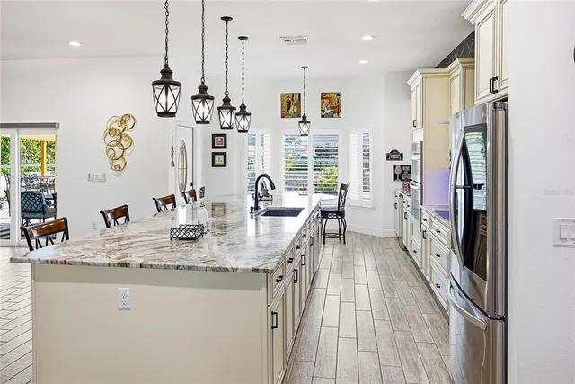 a kitchen with stainless steel appliances a stove a sink a microwave a center island and a refrigerator