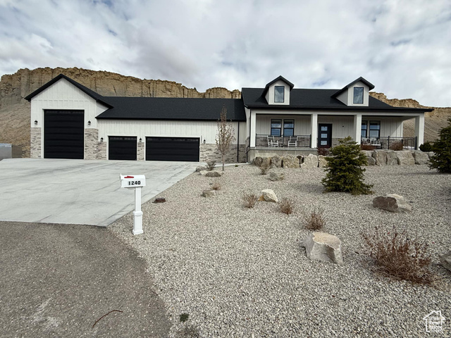 1240 West 2360 North Helper, UT 84526 - Photo 2 of 79 View of front facade featuring driveway, stone siding, a garage, board and batten siding, and a porch