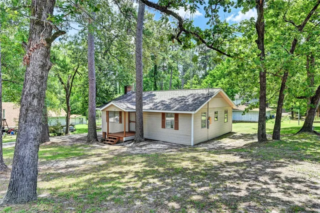 a view of a house with a yard and large trees