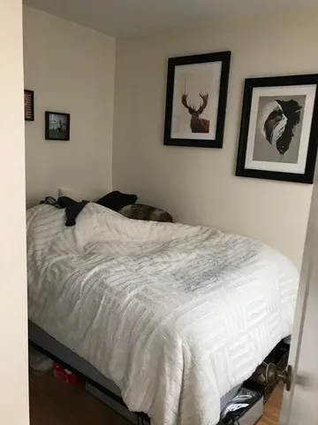a bedroom with a bed and painting on the wall