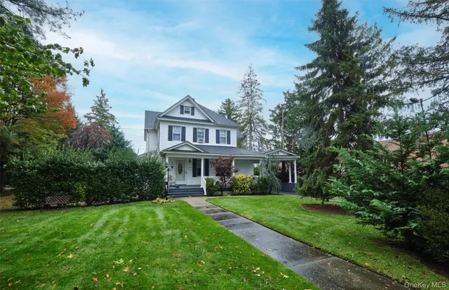 a view of house in front of a big yard with large trees