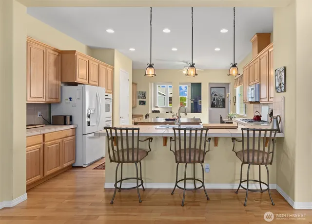 a kitchen with stainless steel appliances kitchen island granite countertop a dining table chairs sink and cabinets