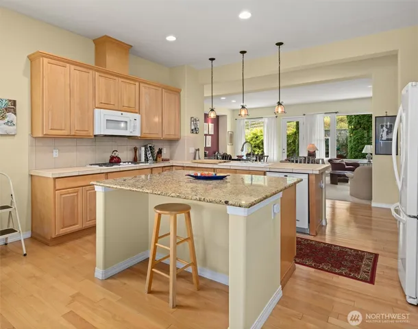 a kitchen with stainless steel appliances granite countertop a stove a sink a oven a dining table and chairs with wooden floor