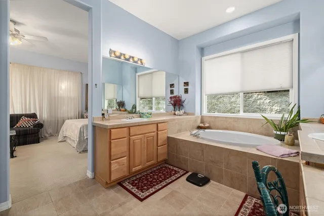 a spacious bathroom with a tub sink and mirror