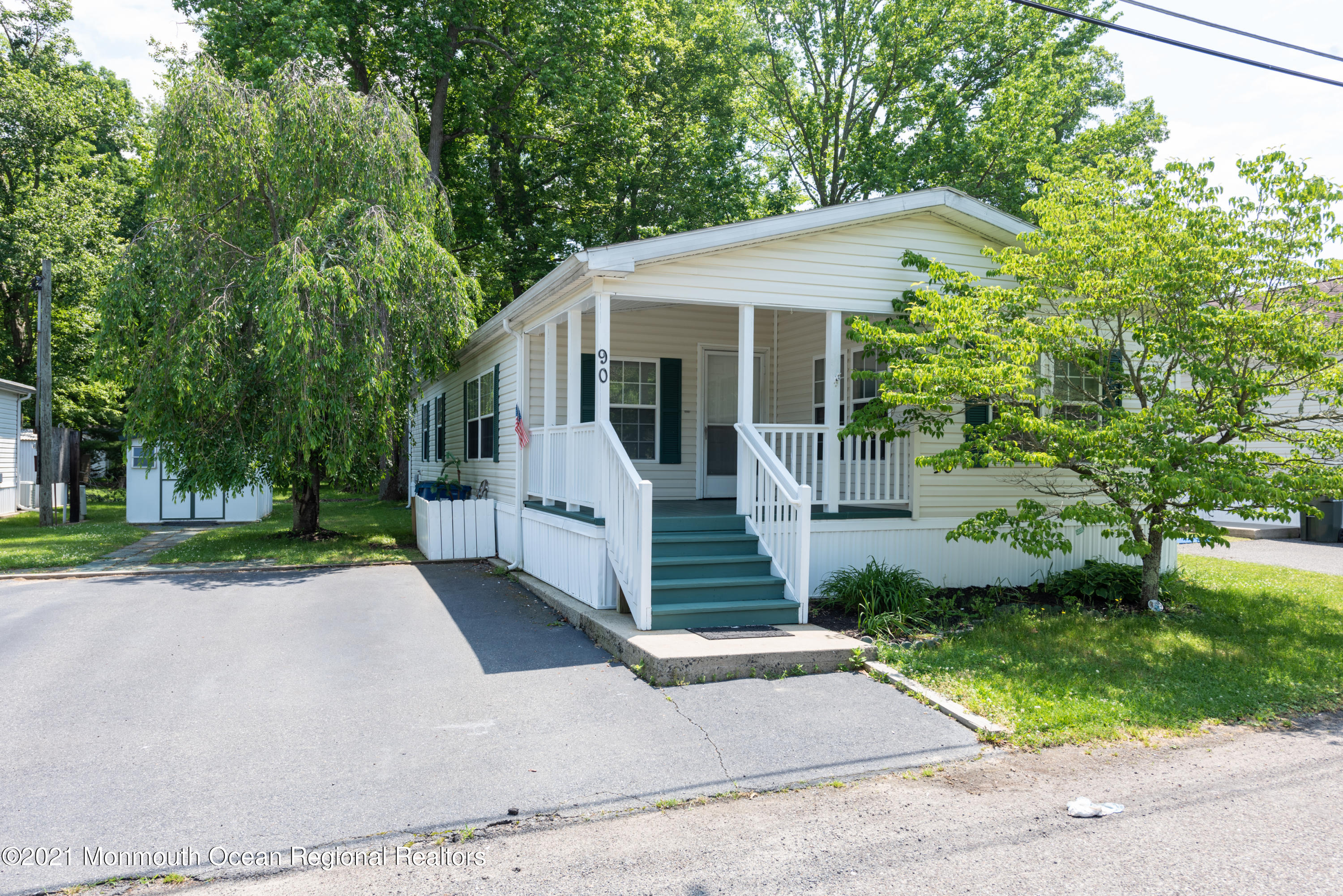 90 Village Road Morganville, NJ 07751 - Photo 1 of 25 a view of a white house with a small yard plants and large trees