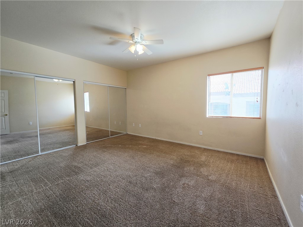 9580 West Reno Avenue, Unit 283 Las Vegas, NV 89148 - Photo 13 of 19 Unfurnished bedroom featuring multiple closets, dark colored carpet, and a ceiling fan