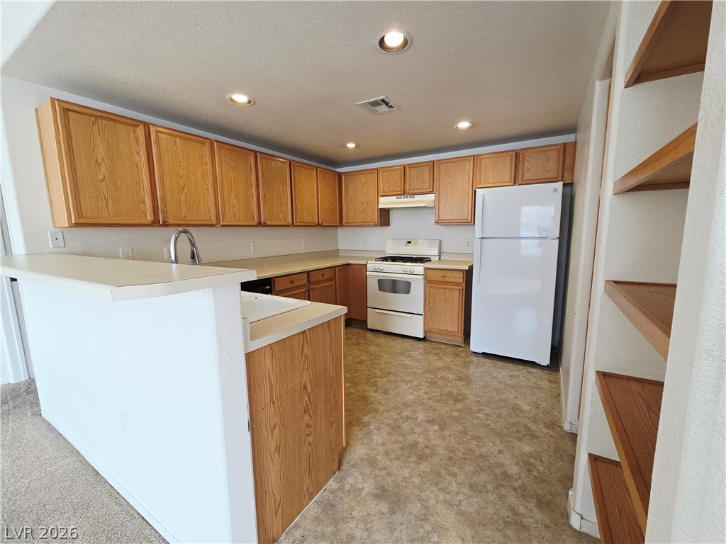 9580 West Reno Avenue, Unit 283 Las Vegas, NV 89148 - Photo 6 of 19 Kitchen featuring white appliances, light countertops, a peninsula, recessed lighting, and light flooring
