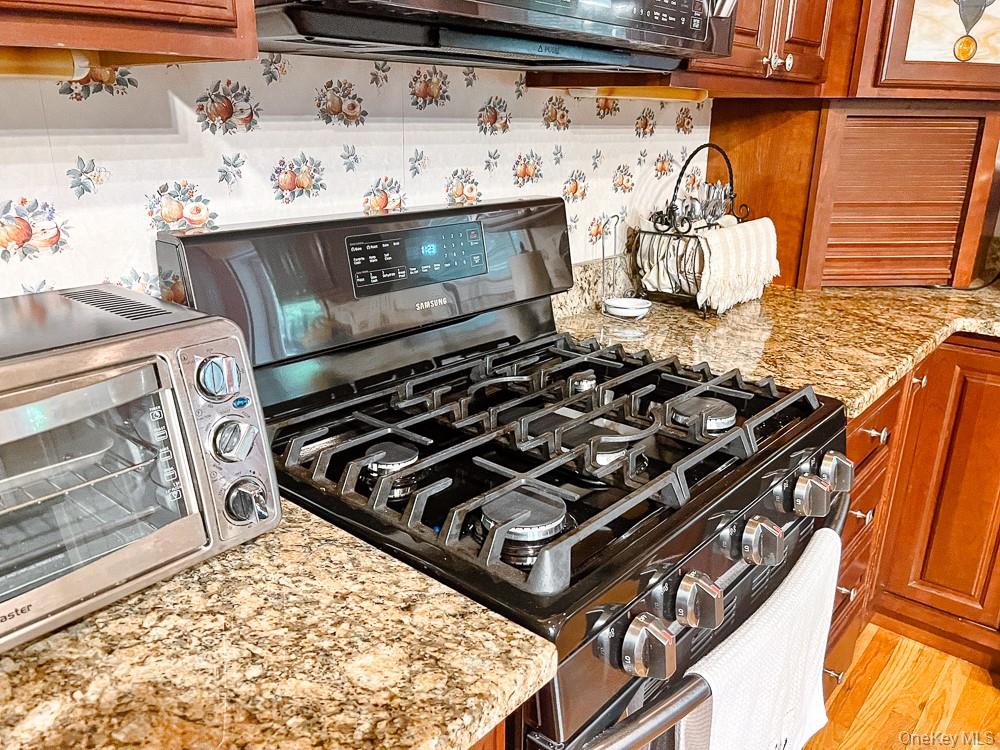 100 Old Tacy Road, Unit TR95 Bethel, NY 12783 - Photo 16 of 50 Kitchen view of range with gas stovetop, brown cabinetry, and light stone counters