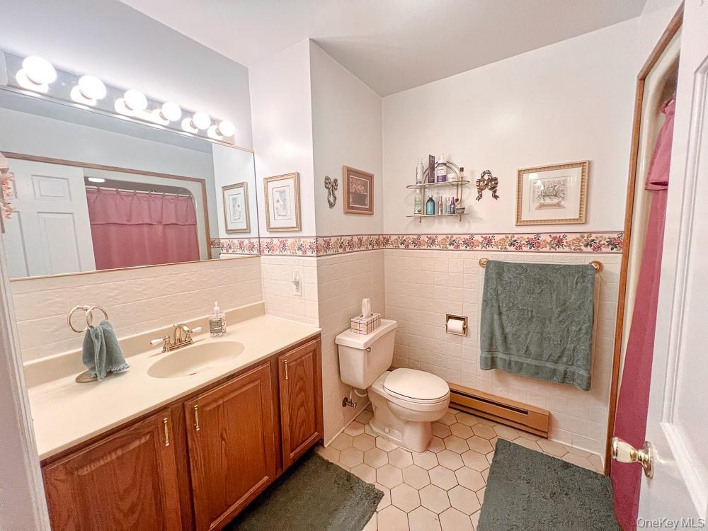 100 Old Tacy Road, Unit TR95 Bethel, NY 12783 - Photo 38 of 50 Bathroom with baseboard heating, vanity, tile patterned floors, wainscoting, and tile walls