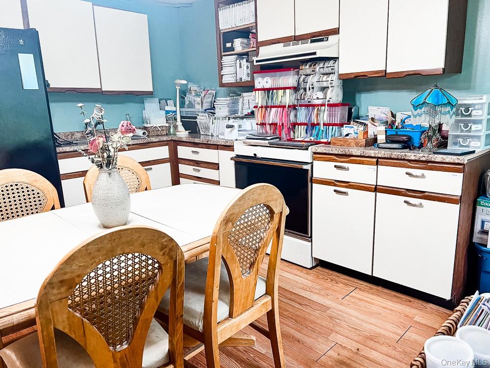 100 Old Tacy Road, Unit TR95 Bethel, NY 12783 - Photo 41 of 50 Kitchen featuring white range with electric stovetop, under cabinet range hood, light wood-style flooring, white cabinets, and freestanding refrigerator