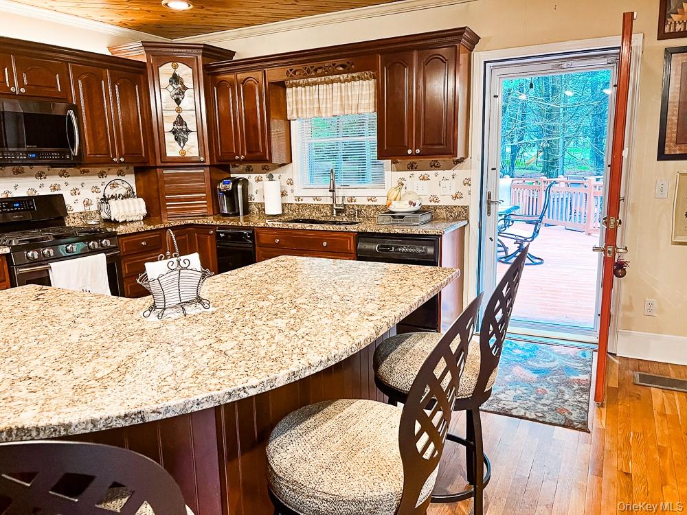 100 Old Tacy Road, Unit TR95 Bethel, NY 12783 - Photo 10 of 50 Kitchen featuring stainless steel microwave, gas range, dishwasher, a kitchen breakfast bar, and light stone countertops