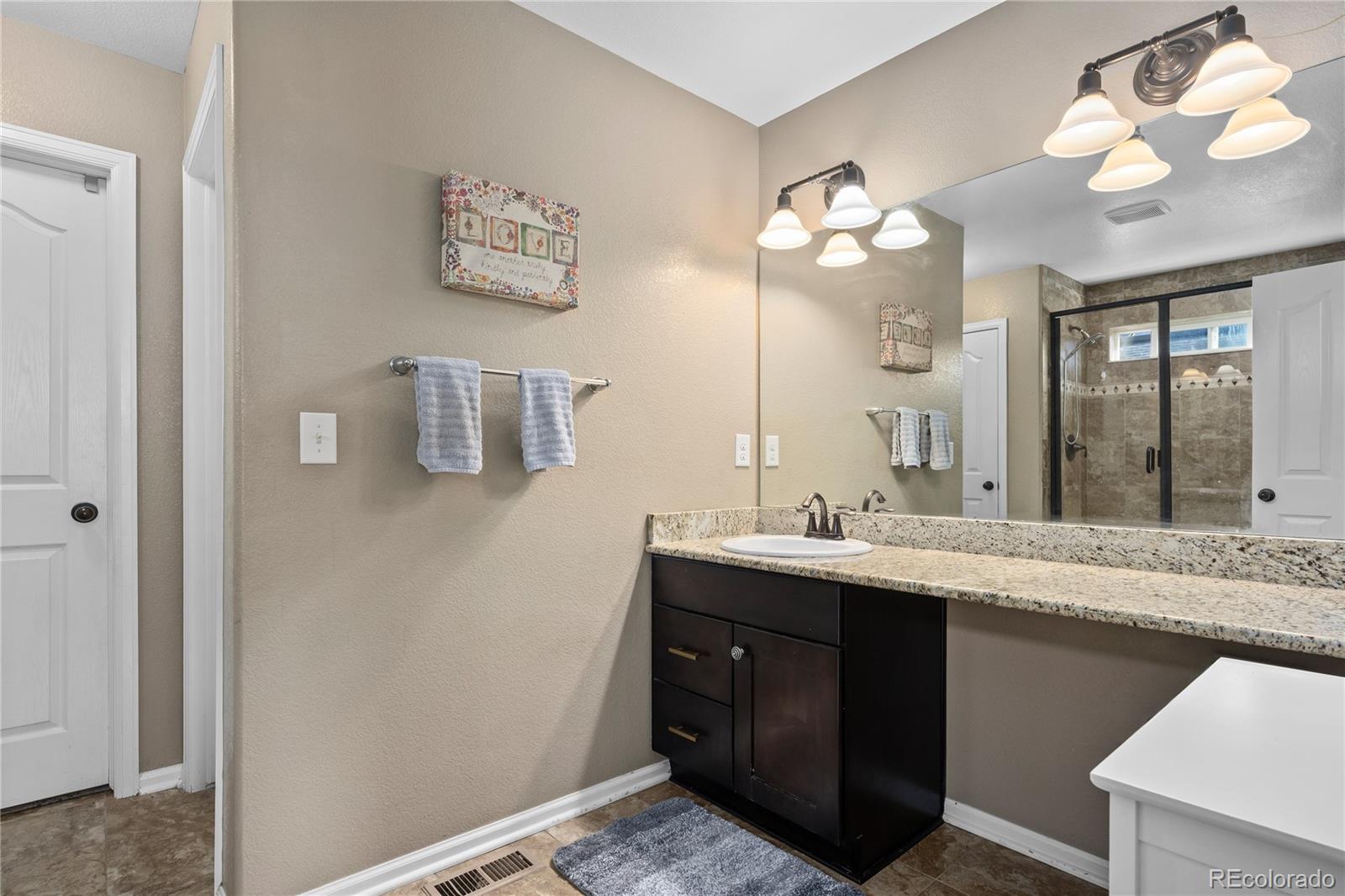 13826 West Layton Circle Morrison, CO 80465 - Photo 28 of 43 a bathroom with a granite countertop sink and a mirror