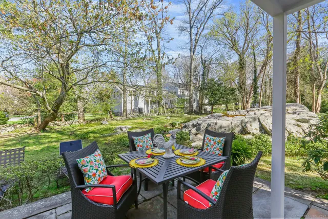 a view of a patio with table and chairs potted plants and large tree