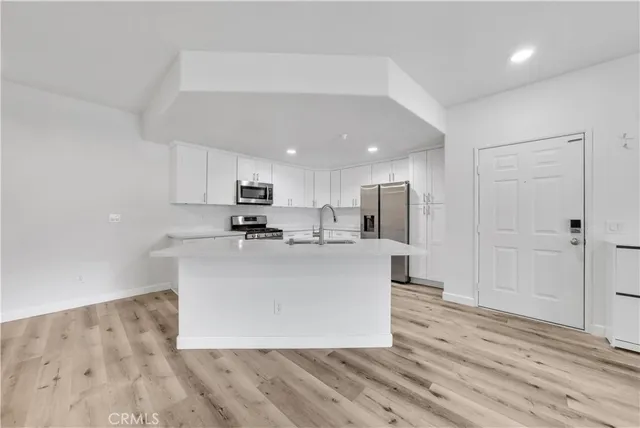 a view of kitchen with stainless steel appliances granite countertop a stove top oven a sink and a refrigerator