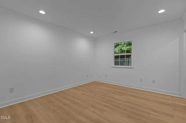 an empty room with wooden floor and a window